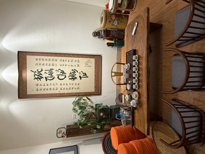 Traditional wooden tea table set with cups beneath framed Vietnamese calligraphy.