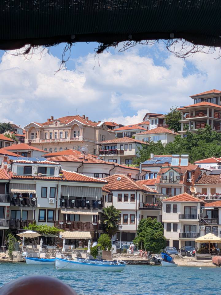 Charming red-tiled rooftops and varied architecture of hillside town under partly cloudy sky.