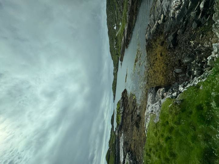 A rocky, sea-weed fringed inlet under a brooding cloudy sky in the Scottish Highlands.