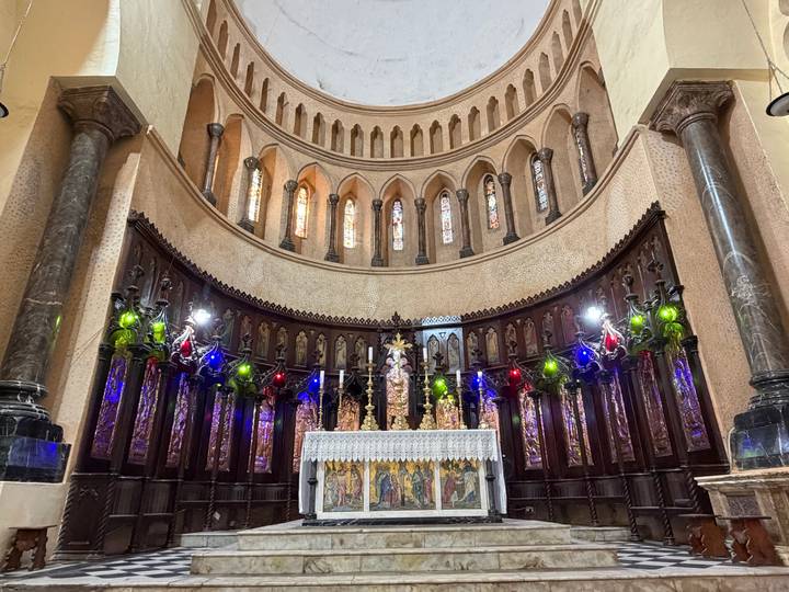 Ornate church altar with colorful lights and gothic arches, captured from central aisle viewpoint.