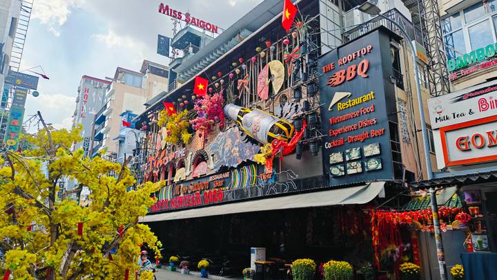 Colorful, densely decorated restaurant and bar façade on a busy Saigon street with Tet ornaments.