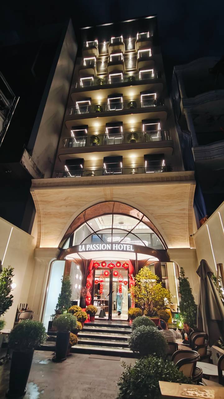 Night view looking up at the warmly lit entrance arch of La Passion Hotel.