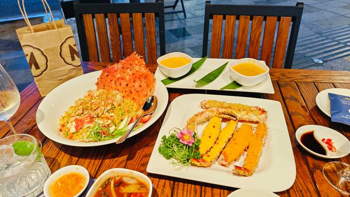 Seafood feast featuring crab fried rice and crab meat dishes served on wooden table.
