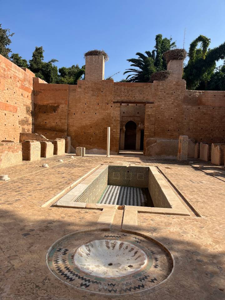 Historic hammam or bath ruins with empty tiled pool and arched doorway.