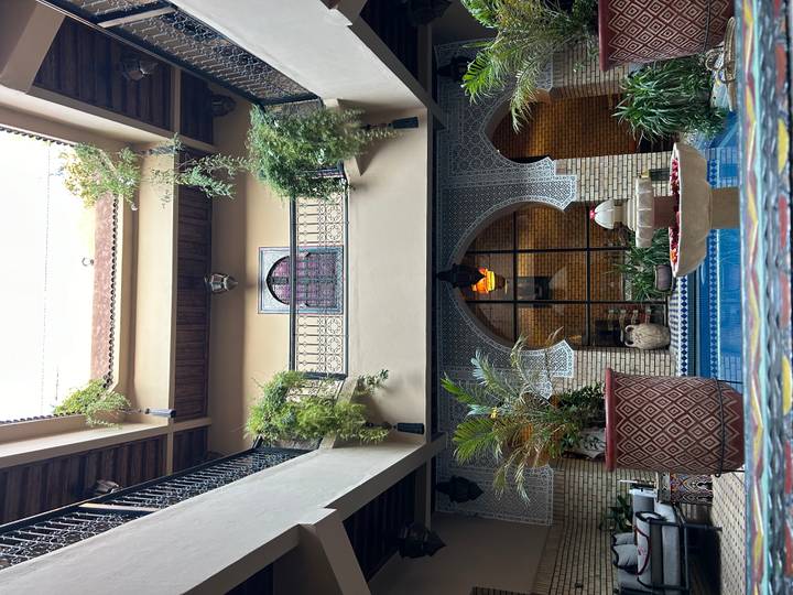 Interior courtyard of traditional riad with tiled pool, arches and hanging plants in Marrakesh
