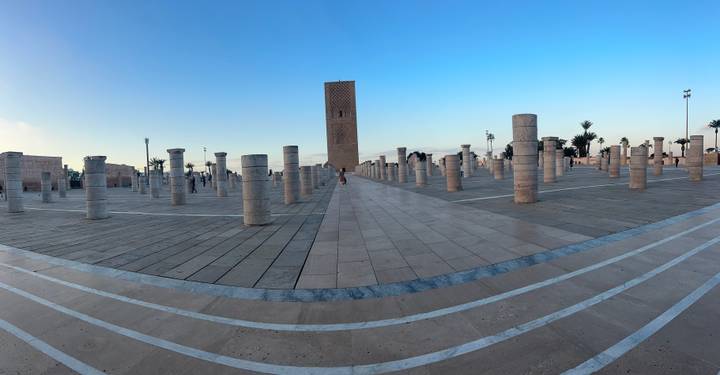 Panoramic view of Hassan Tower plaza in Rabat with lone visitor among stone columns at dusk