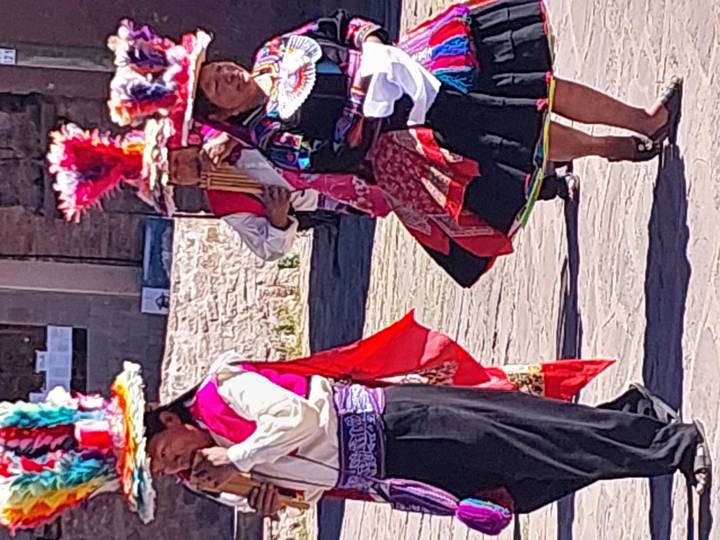 Traditional Peruvian dancers in bright costumes and headdresses performing outdoors, partial view