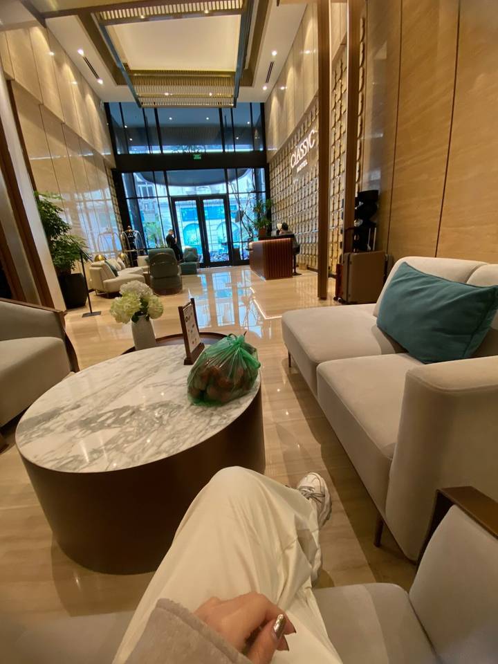 Modern hotel lobby with marble coffee table, plush armchairs and large windows overlooking a city street