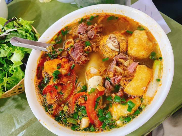 Vibrant bowl of Vietnamese noodle soup with assorted meats, herbs and vegetables