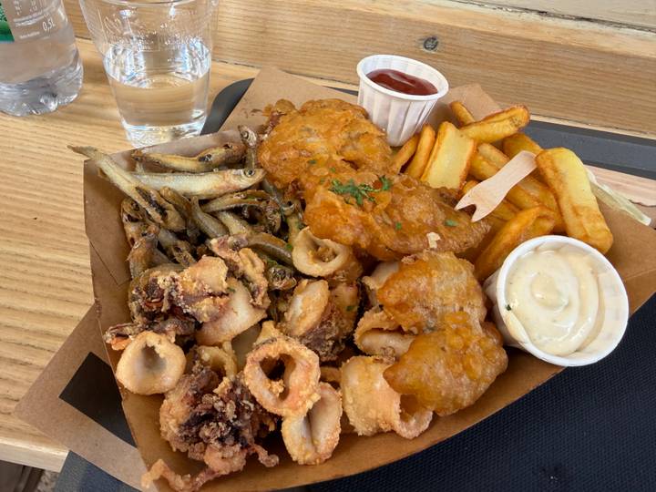 Box of assorted fried seafood, chips and dipping sauces on a wooden table