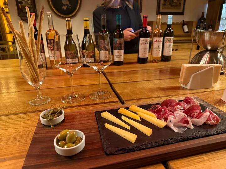 Wine and cheese tasting setup with glasses, olives and charcuterie on a wooden table