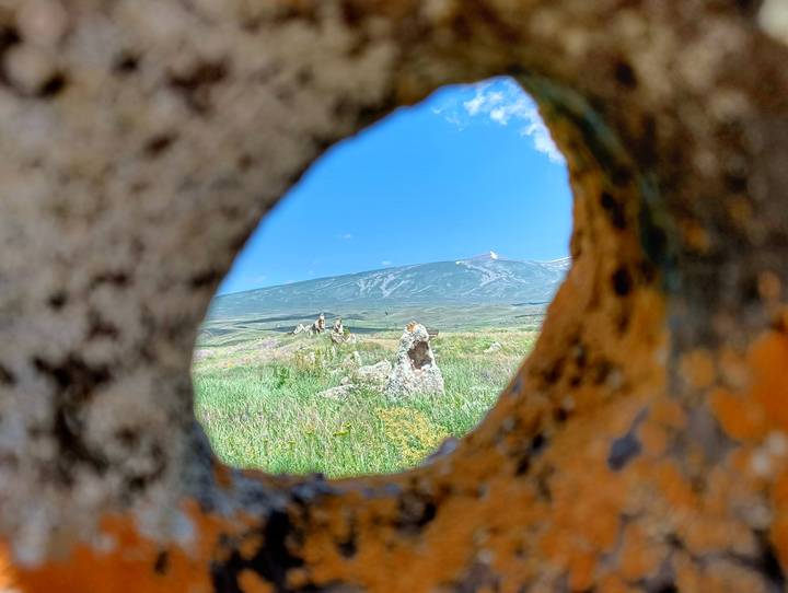 Mountain landscape seen through a circular opening in an ancient stone