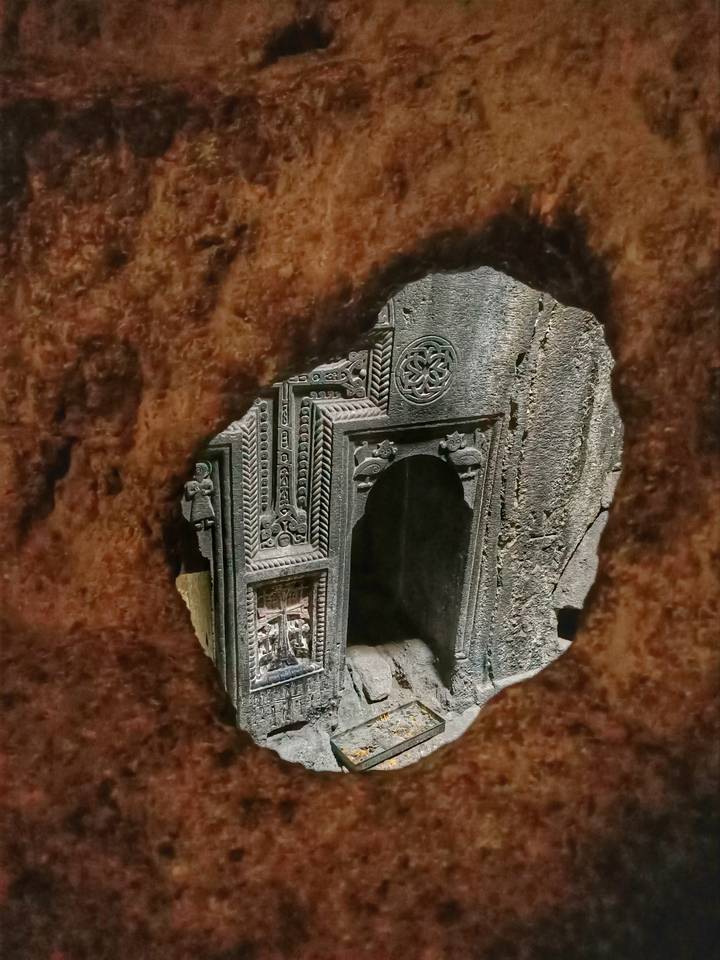 Detailed Armenian stone carving viewed through a natural rock window
