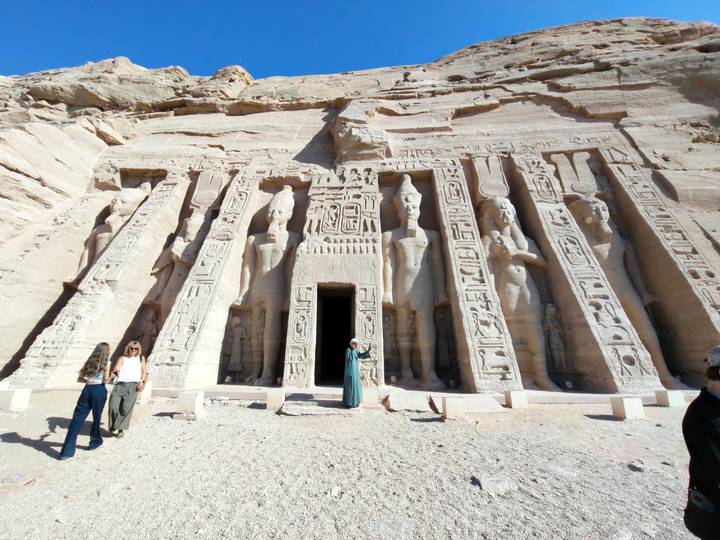 Facade of Abu Simbel’s smaller rock temple with massive statues and tourists standing at the entrance