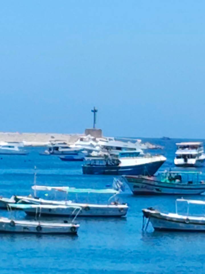 Soft-focus image of pleasure boats moored on vivid blue water near a low sea wall