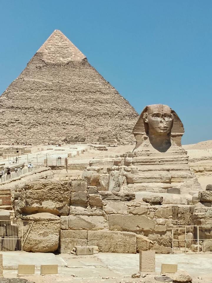 Classic profile of the Great Sphinx with the Great Pyramid towering behind under blue sky