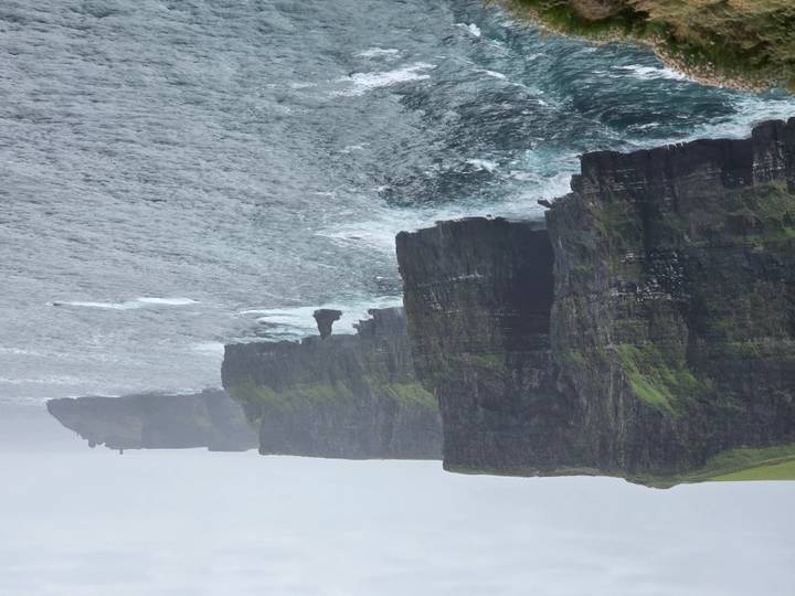 Dramatic view of the Cliffs of Moher plunging into a choppy Atlantic under grey skies