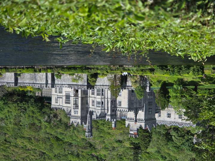 Picturesque Kylemore Abbey reflected across a calm lake framed by rich greenery