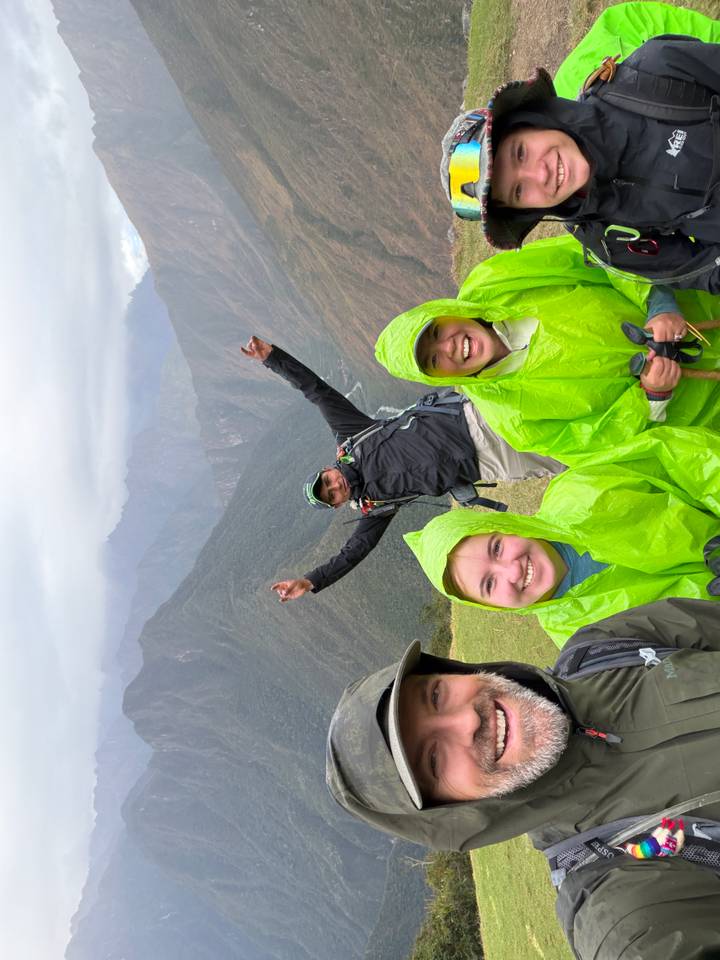 Trekkers in bright green rain ponchos celebrating on a misty Andean ridge