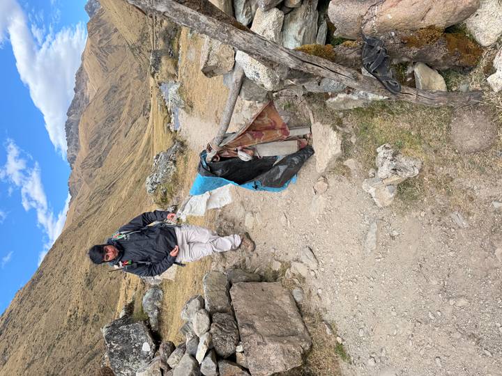 Trekker walking along a stony mountain path with simple stone walls
