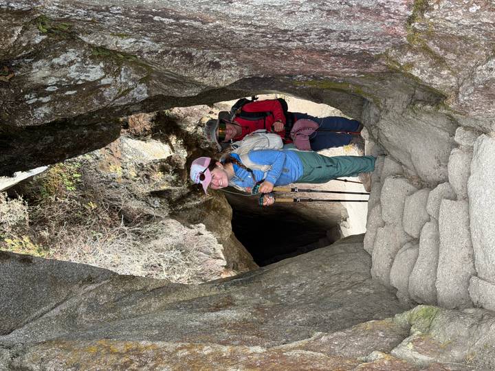 Trekker emerging through a narrow rock tunnel on the Inca trail