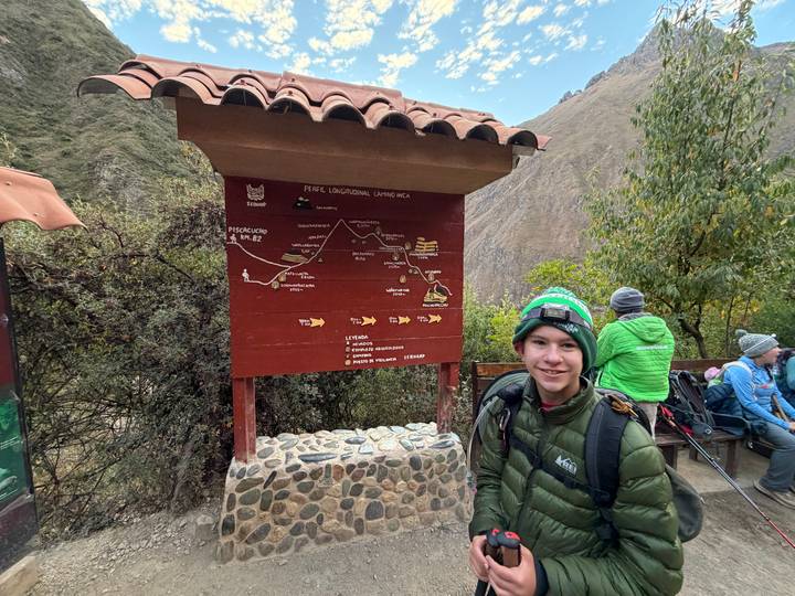 Young hiker standing beside an information signboard that maps the Inca trail route