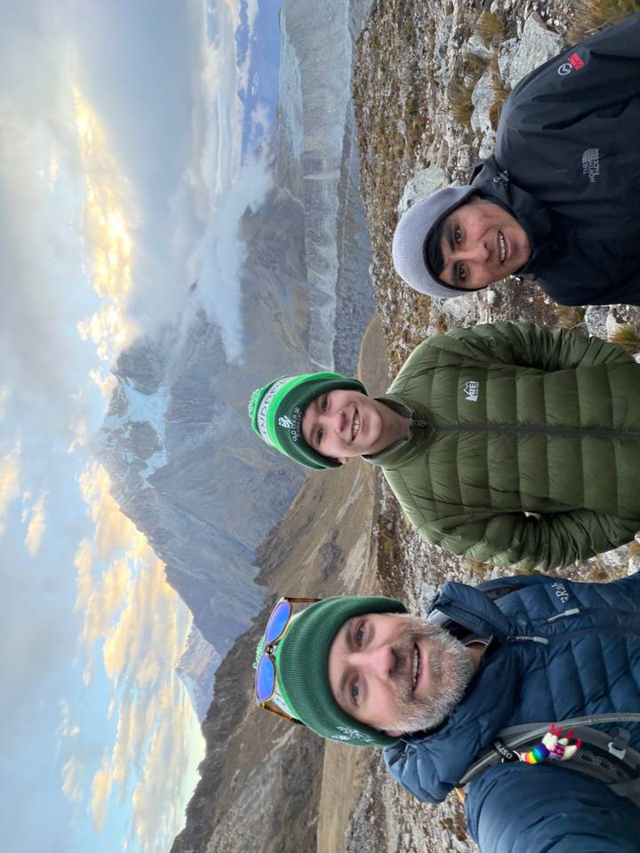 Teen hiker smiling in front of snow-capped mountain at sunrise with colourful sky