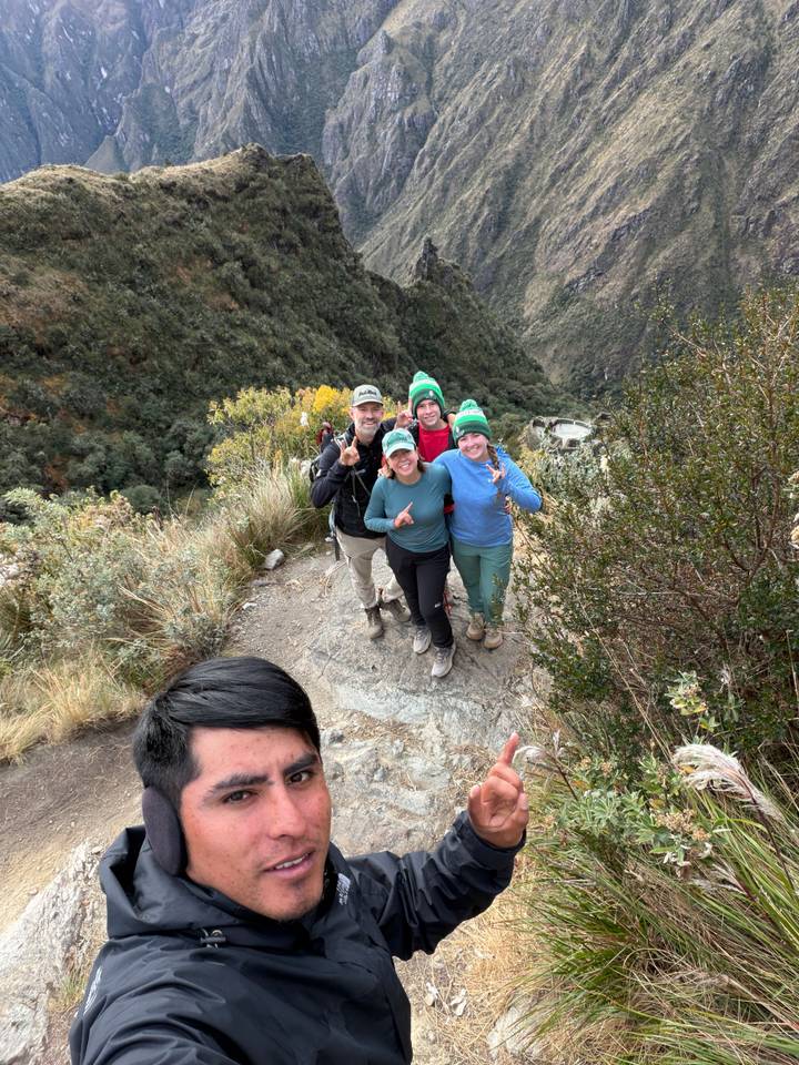 Family of trekkers posing on a rocky viewpoint above a lush ravine