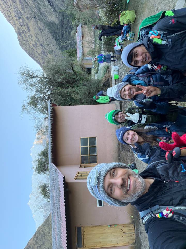 Bundled up trekkers flash peace signs outside a frosty rural lodge at dawn.