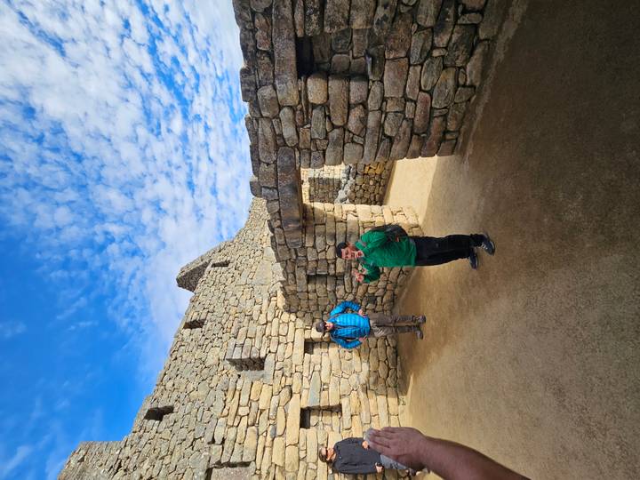 A guide explains Inca stonework inside Machu Picchu ruins under a patterned sky.