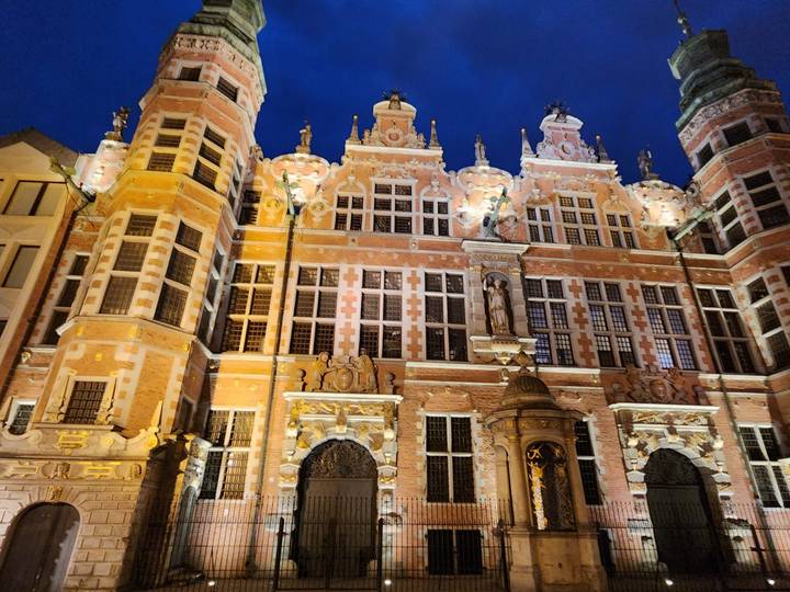 Illuminated ornate Renaissance-style façade of a historic building glows against a deep night sky.
