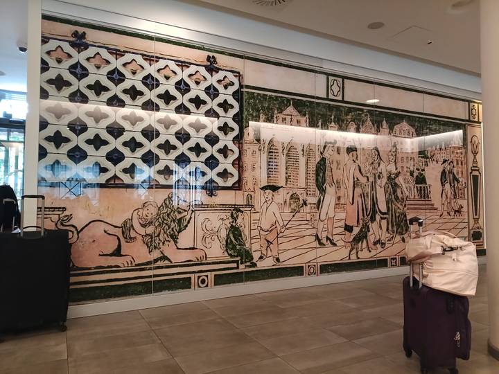 Large decorative wall mural of historic figures and patterns inside a modern building lobby.