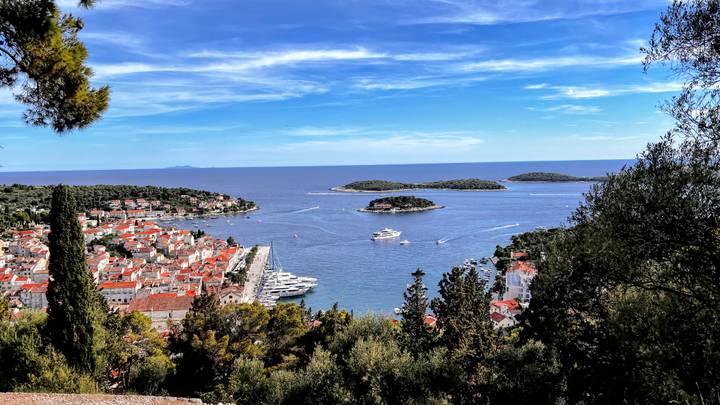Aerial view of Hvar town’s red rooftops, marina and surrounding islets under a vivid blue sky