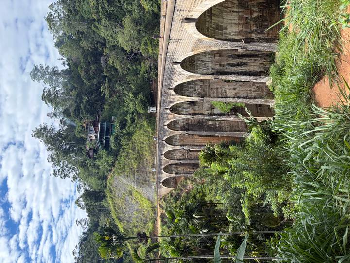 Iconic Nine Arches railway bridge spans a deep jungle ravine with misty hills behind.