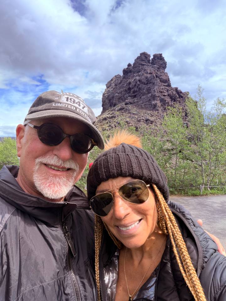 Selfie with volcanic rock outcrop and green shrubs in the background