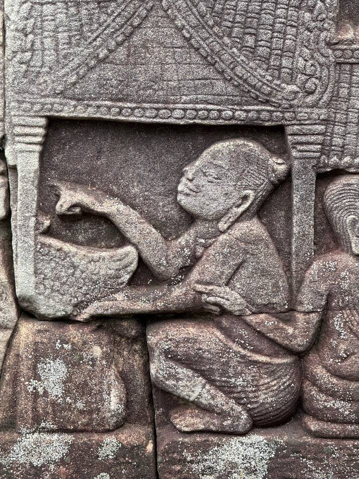 Detailed close-up of an ancient sandstone bas-relief carving of a seated figure