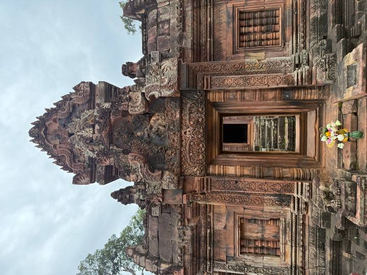 Intricately carved doorway of Banteay Srei temple with flower offering at the base