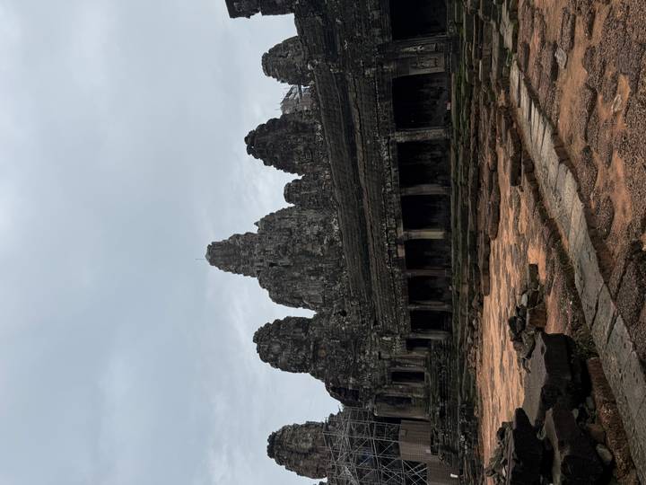 Dark, moody view of Bayon-style temple towers under a grey sky