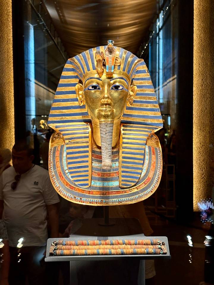 The golden funerary mask of Tutankhamun on display inside a museum gallery.