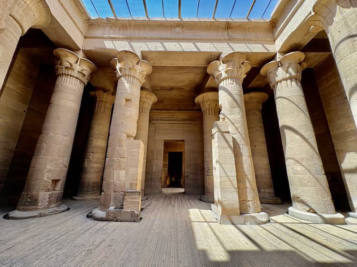 Sunbeams light intricately carved stone columns inside an ancient Egyptian temple.