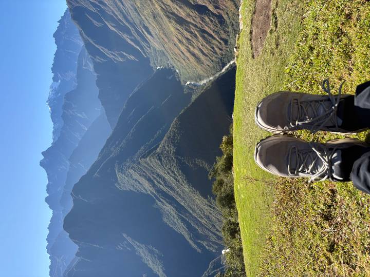 Traveler's shoes in foreground overlooking steep Andean valley and winding river.
