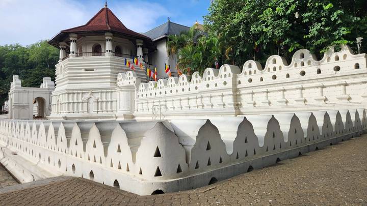 White crenellated walls and a red-roofed octagonal tower of the Temple of the Tooth in Kandy.
