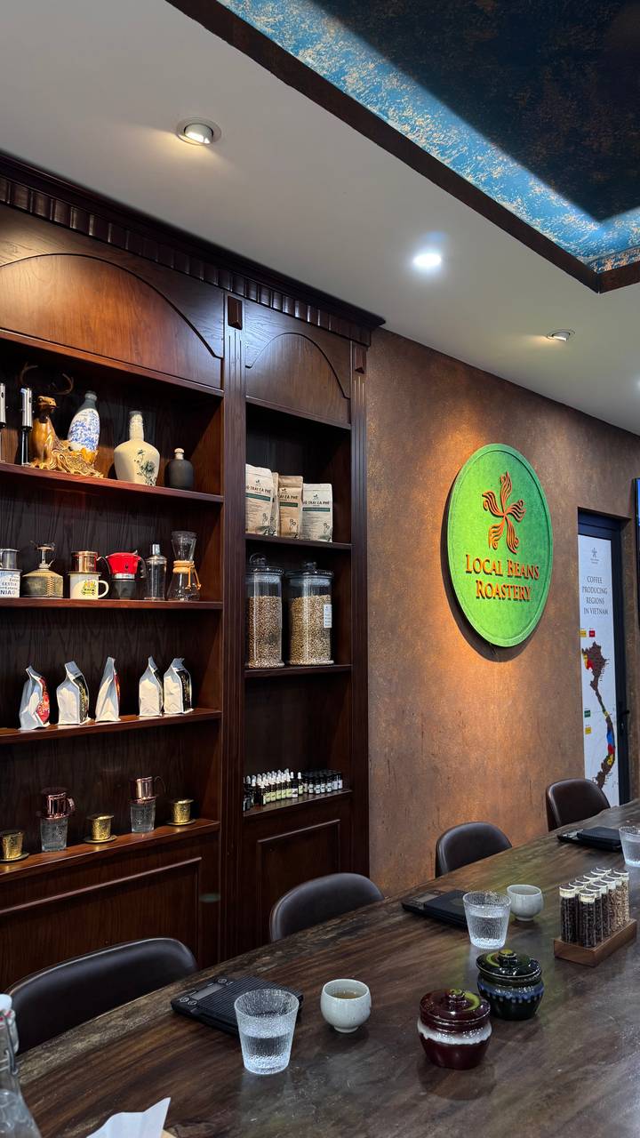 Interior of a coffee roastery with shelves of beans, equipment and a green round sign reading 'Local Beans Roastery'