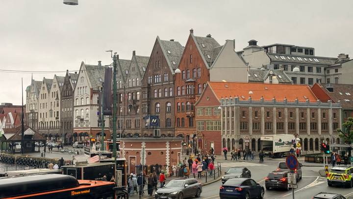 Historic Bryggen wharf in Bergen with rows of colorful gabled wooden warehouses lining a busy street.
