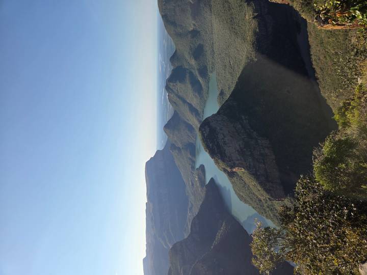Panoramic viewpoint over Blyde River Canyon with deep green valleys and winding blue reservoir.