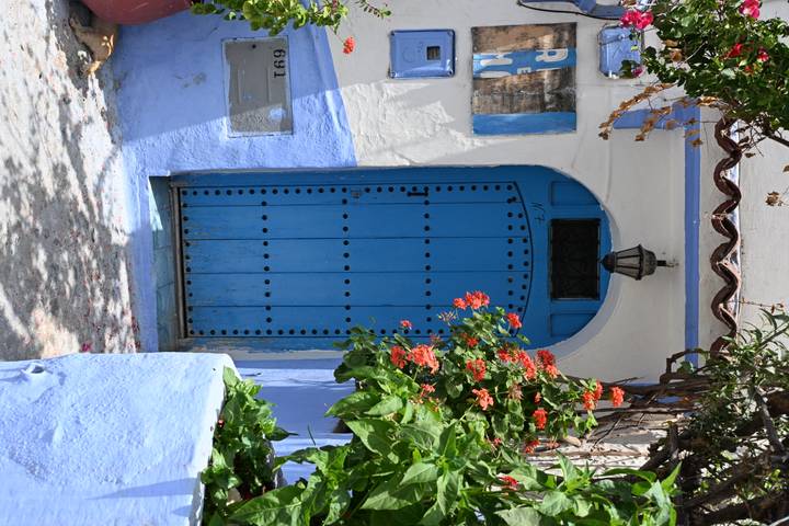 Bright blue arched doorway adorned with flowers in the medina of Chefchaouen.