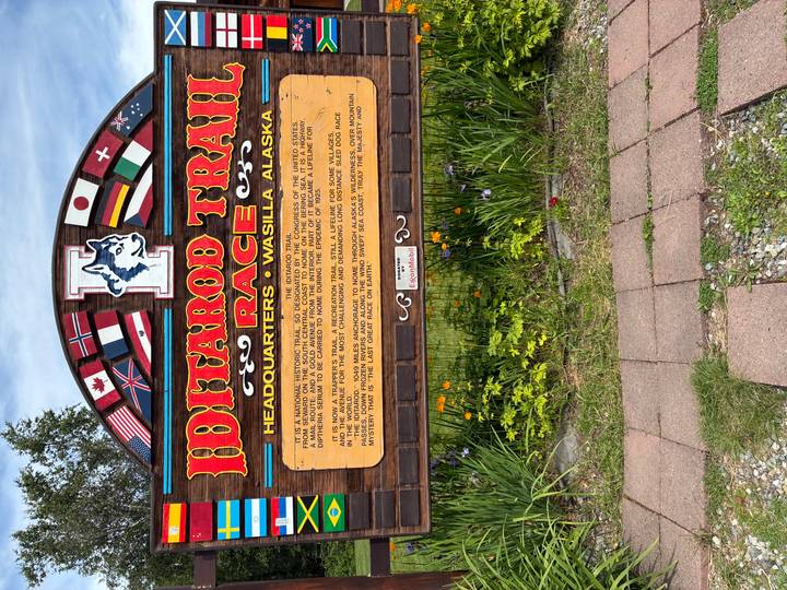Colorful Iditarod Trail Race headquarters sign decorated with international flags in Wasilla, Alaska.