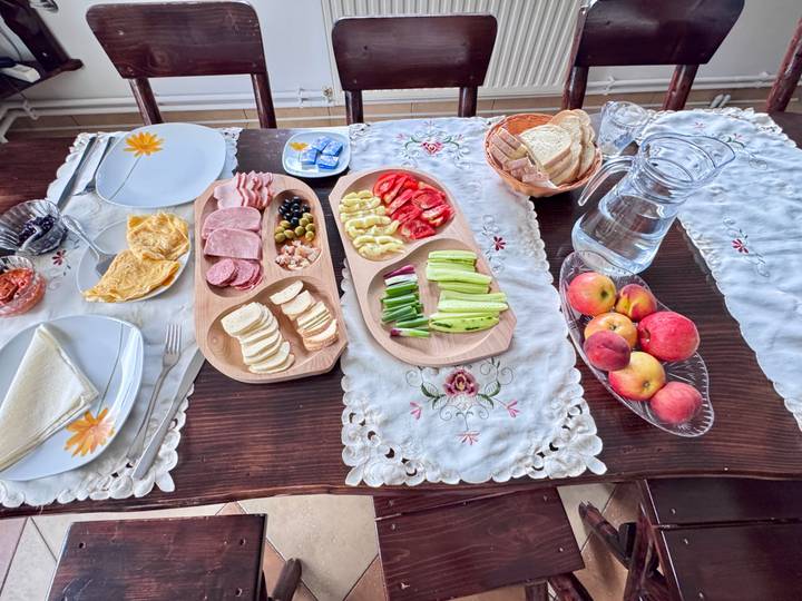 Breakfast spread of cold cuts, cheese, vegetables and fruit beautifully arranged on a lace-draped table.