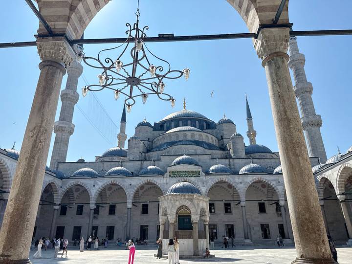 Courtyard view of the Blue Mosque with arches and domes framed by stone columns