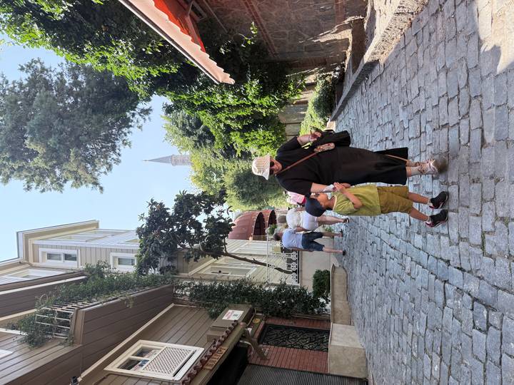 Cobbled uphill street with tourists; mother and child holding hands in the foreground